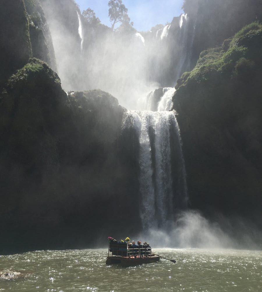 Stunning view of Ouzoud Falls in Morocco with tourists on a raft below the cascading waterfalls.